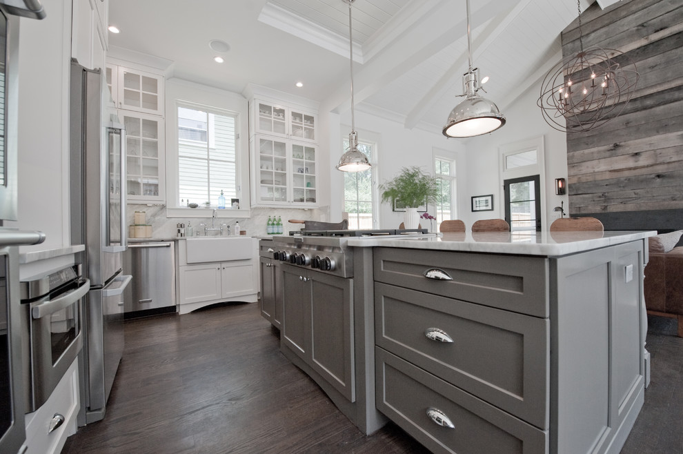 Example of a large transitional l-shaped dark wood floor and brown floor eat-in kitchen design in Atlanta with an island, shaker cabinets, white cabinets, marble countertops, white backsplash, stone slab backsplash, stainless steel appliances and a farmhouse sink