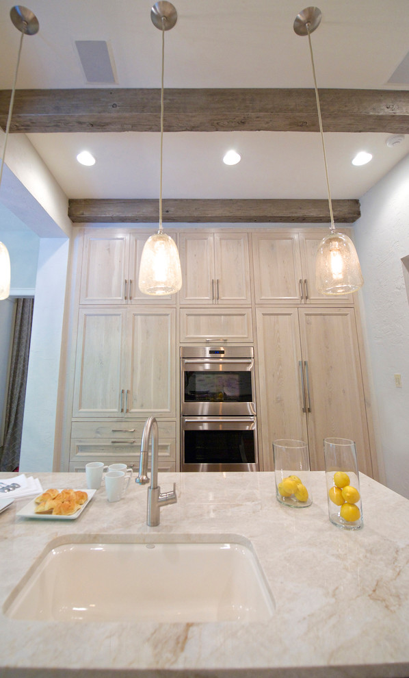 Bild på ett avskilt, stort vintage vit vitt u-kök, med en undermonterad diskho, luckor med infälld panel, skåp i ljust trä, bänkskiva i kvartsit, vitt stänkskydd, stänkskydd i stenkakel, integrerade vitvaror, mellanmörkt trägolv, en köksö och brunt golv
