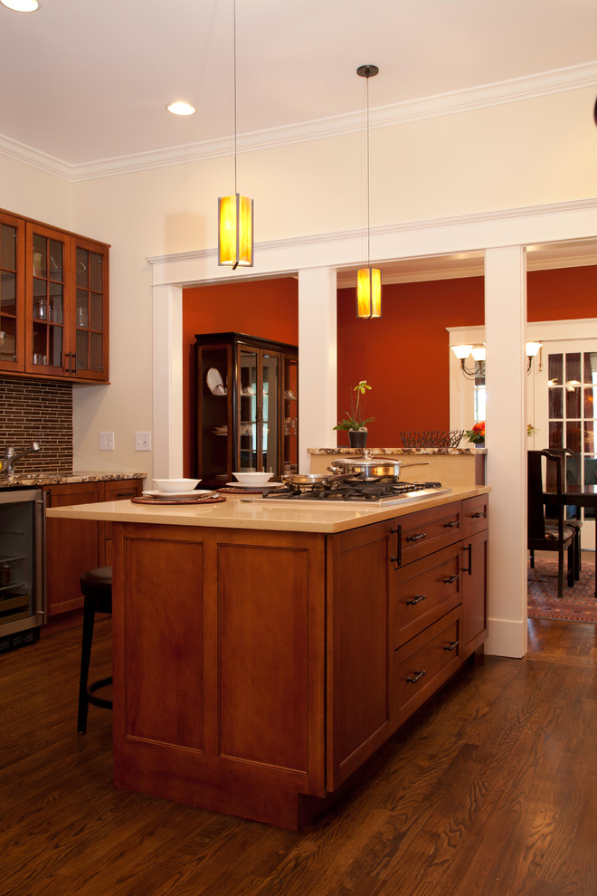 Eat-in kitchen - mid-sized craftsman dark wood floor and brown floor eat-in kitchen idea in New Orleans with beaded inset cabinets, medium tone wood cabinets, brown backsplash, mosaic tile backsplash, stainless steel appliances, an island and beige countertops
