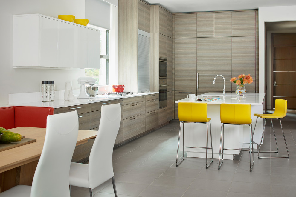 Photo of a medium sized modern grey and cream l-shaped open plan kitchen in Atlanta with a submerged sink, flat-panel cabinets, grey cabinets, engineered stone countertops, white splashback, stainless steel appliances, porcelain flooring, an island, grey floors and glass sheet splashback.