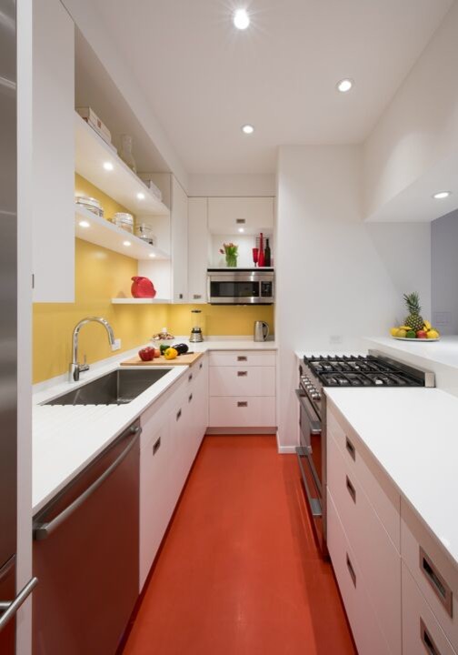 Idéer för avskilda, små funkis u-kök, med en undermonterad diskho, släta luckor, vita skåp, bänkskiva i koppar, gult stänkskydd, glaspanel som stänkskydd, rostfria vitvaror, linoleumgolv, en halv köksö och rött golv