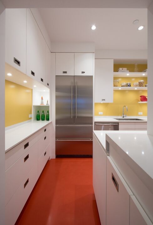 ニューヨークにある高級な小さなモダンスタイルのおしゃれなキッチン (アンダーカウンターシンク、フラットパネル扉のキャビネット、白いキャビネット、人工大理石カウンター、黄色いキッチンパネル、ガラス板のキッチンパネル、シルバーの調理設備、リノリウムの床、赤い床) の写真