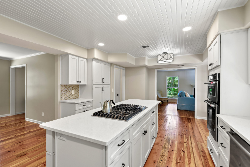 Foto di un cucina con isola centrale chic con paraspruzzi multicolore, elettrodomestici in acciaio inossidabile, top bianco e soffitto in perlinato