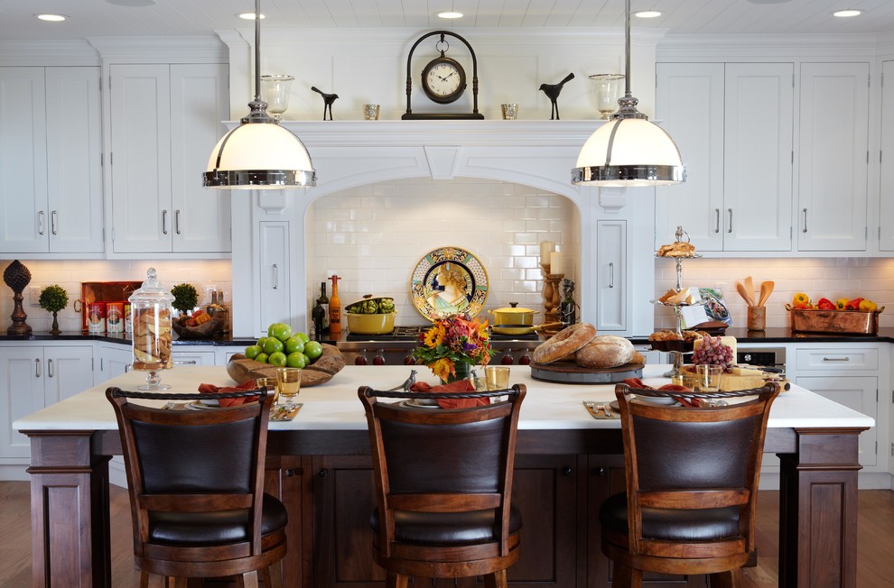 Large elegant l-shaped medium tone wood floor eat-in kitchen photo in New York with a farmhouse sink, white cabinets, onyx countertops, white backsplash, paneled appliances, an island, recessed-panel cabinets and subway tile backsplash