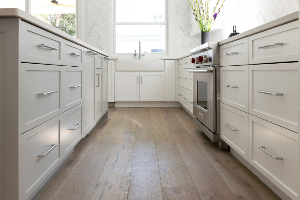 Imagen de cocina lineal tradicional renovada con armarios con paneles con relieve, salpicadero blanco y salpicadero de mármol