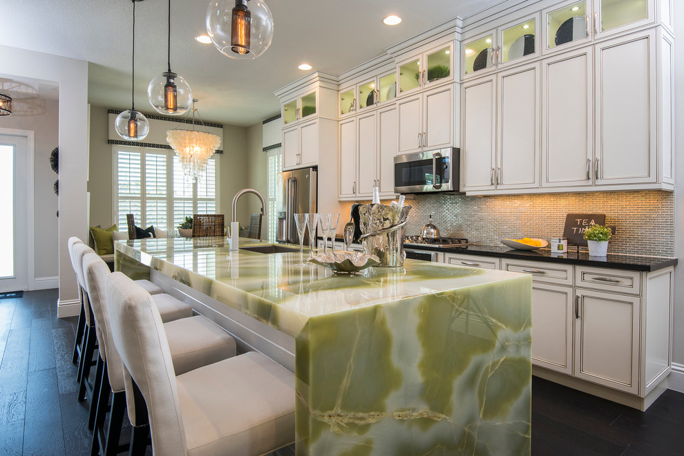 Immagine di una cucina tropicale con lavello sottopiano, ante a filo, ante bianche, paraspruzzi grigio, elettrodomestici in acciaio inossidabile, parquet scuro e top verde