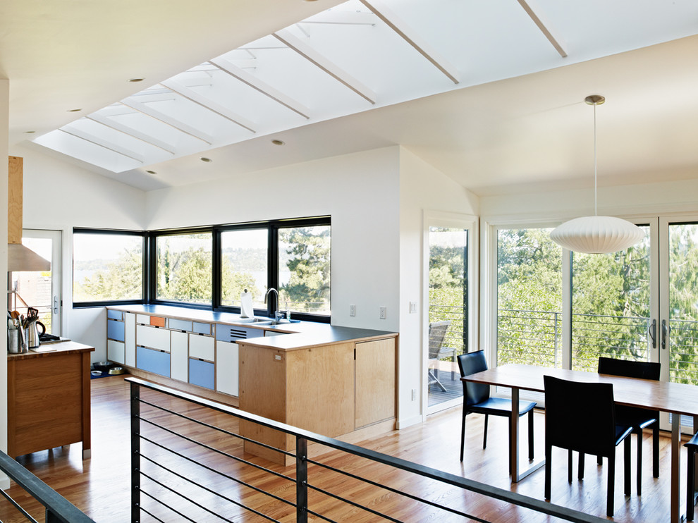 Midcentury kitchen/diner in Seattle with a double-bowl sink, flat-panel cabinets and blue cabinets.