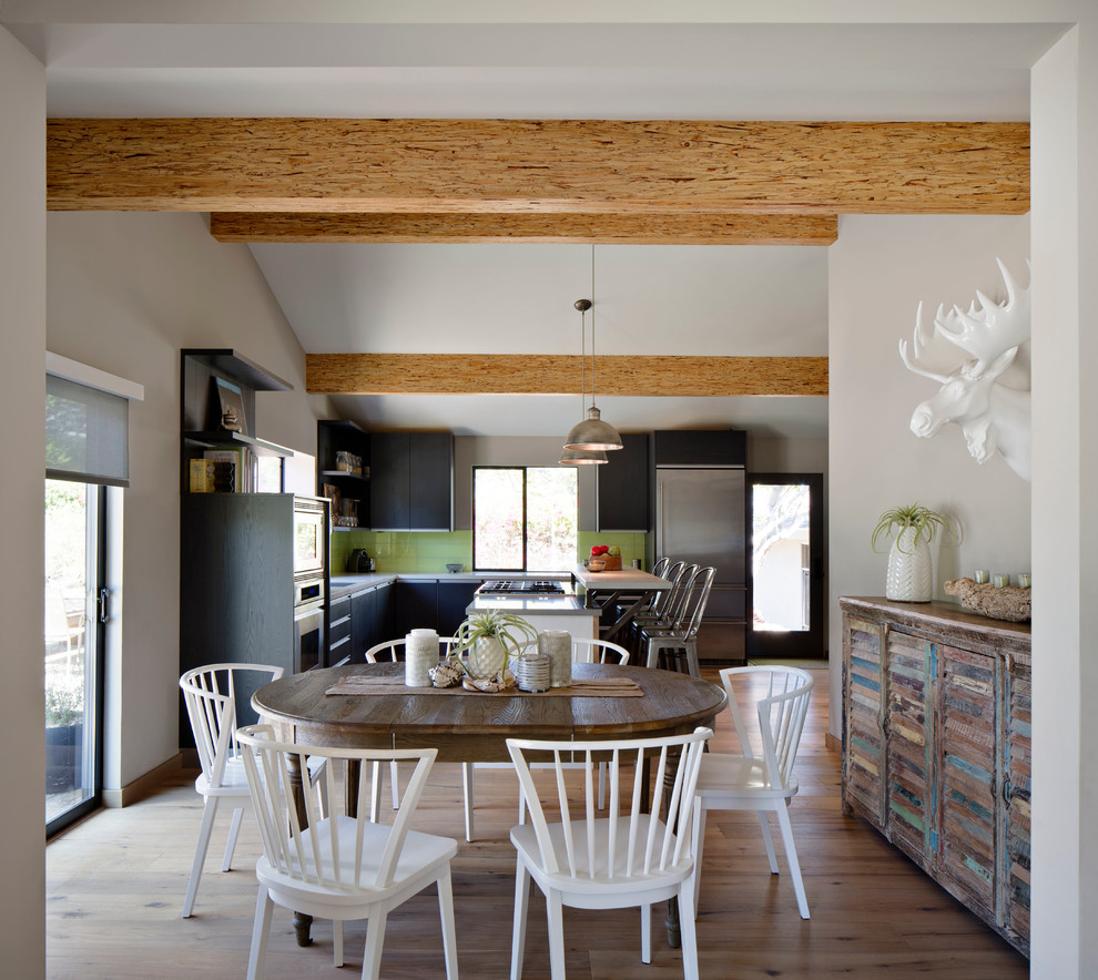 Foto di una cucina minimal di medie dimensioni con ante lisce, ante nere, paraspruzzi verde, elettrodomestici in acciaio inossidabile e parquet chiaro