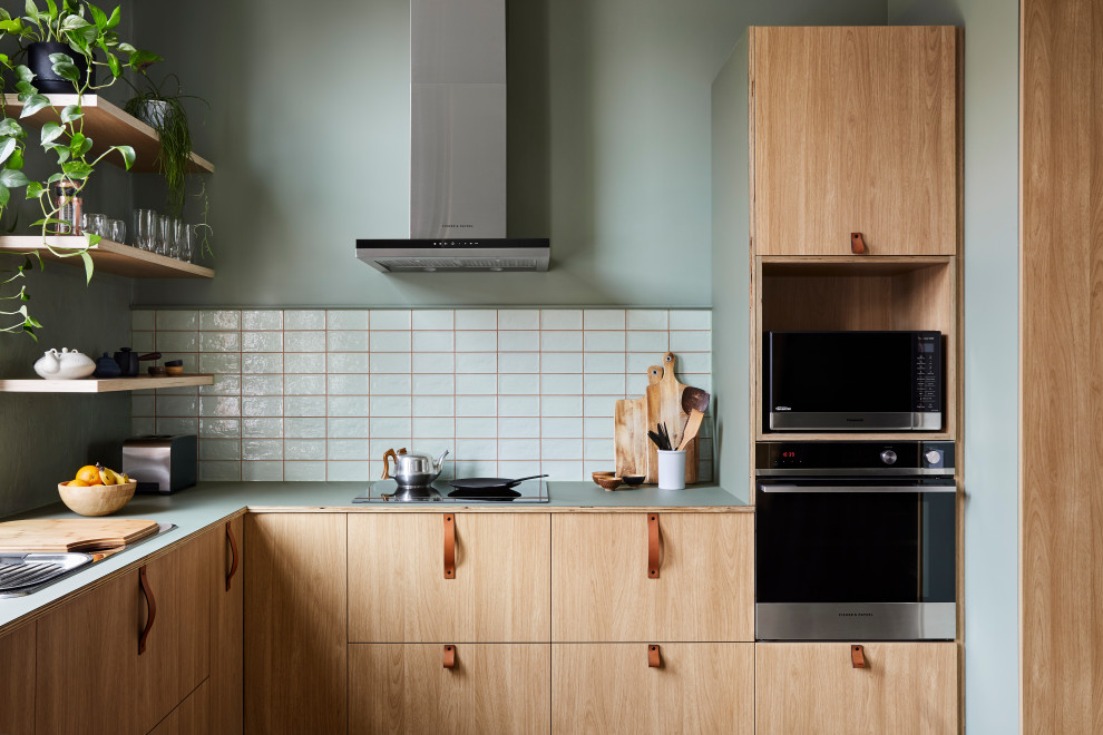 メルボルンにあるコンテンポラリースタイルのおしゃれなL型キッチン (フラットパネル扉のキャビネット、淡色木目調キャビネット、白いキッチンパネル、シルバーの調理設備、緑のキッチンカウンター) の写真