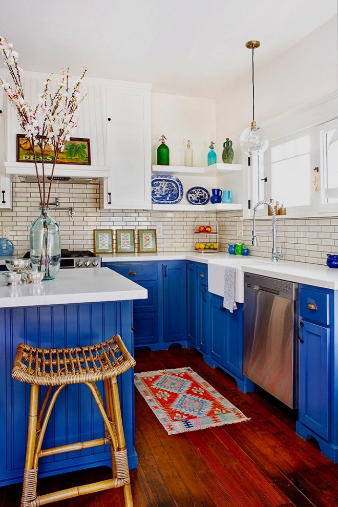 Mid-sized arts and crafts l-shaped dark wood floor and brown floor enclosed kitchen photo in Los Angeles with a farmhouse sink, shaker cabinets, blue cabinets, quartz countertops, white backsplash, ceramic backsplash, stainless steel appliances, an island and white countertops