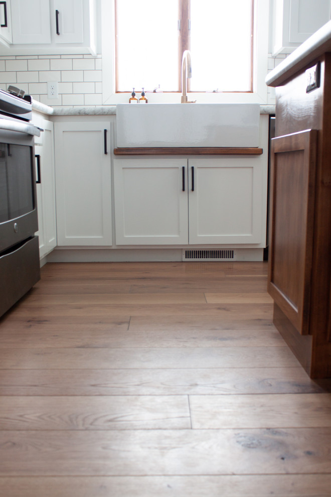 Example of a cottage light wood floor and white floor kitchen design in Nashville with medium tone wood cabinets, white backsplash, subway tile backsplash and stainless steel appliances
