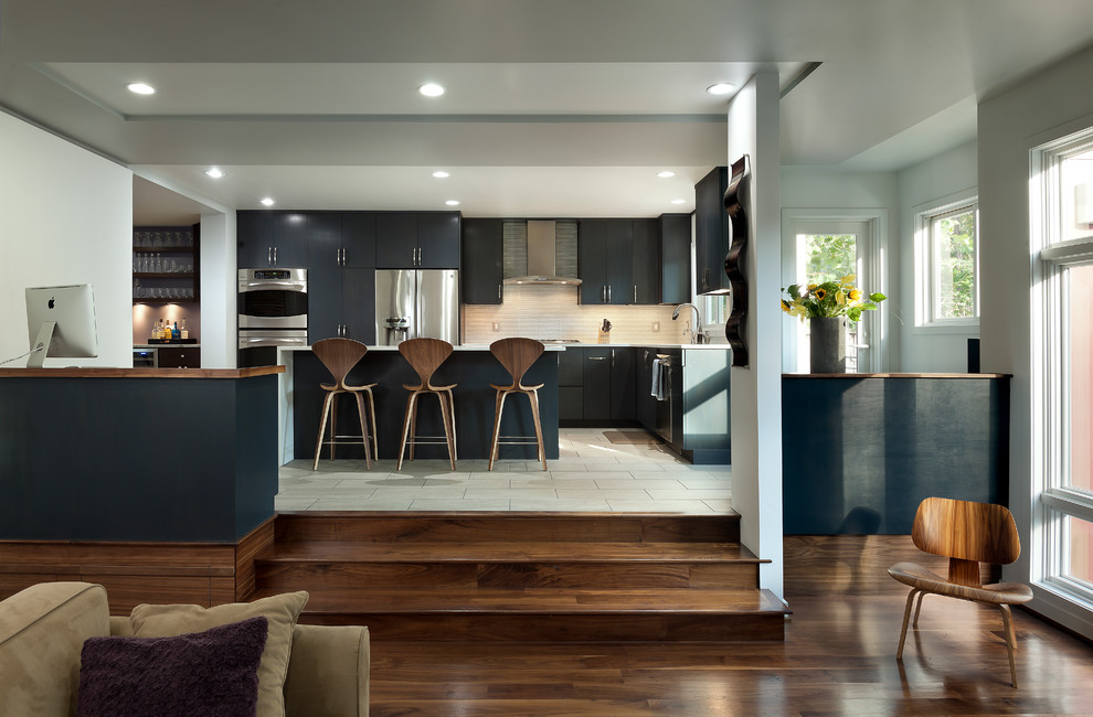 This is an example of a contemporary l-shaped kitchen/diner in DC Metro with flat-panel cabinets, black cabinets, stainless steel appliances and an island.