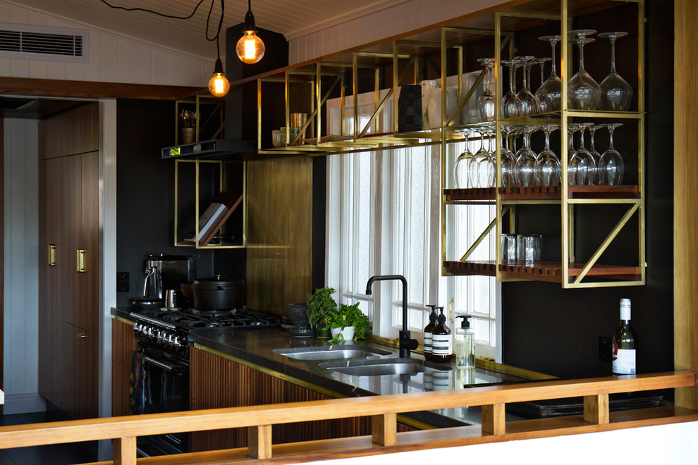 Foto di una cucina industriale con lavello sottopiano, ante a persiana, ante in legno scuro, top in granito, elettrodomestici neri e top grigio