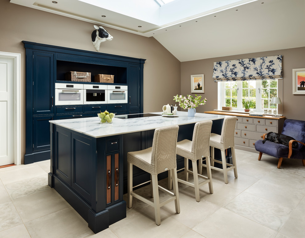 Design ideas for a medium sized traditional kitchen in Essex with beaded cabinets, blue cabinets, marble worktops, white appliances, an island and grey floors.