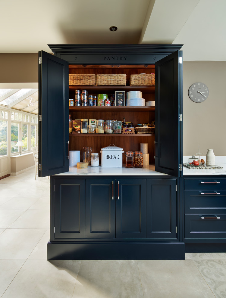 エセックスにある広いトラディショナルスタイルのおしゃれなアイランドキッチン (インセット扉のキャビネット、青いキャビネット、大理石カウンター、白い調理設備) の写真