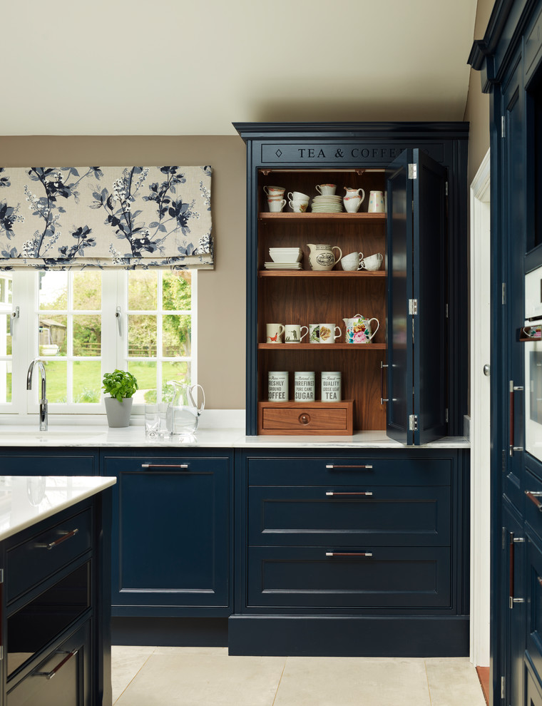 Cette photo montre une grande cuisine chic avec un placard à porte affleurante, des portes de placard bleues, plan de travail en marbre, un électroménager blanc et îlot.