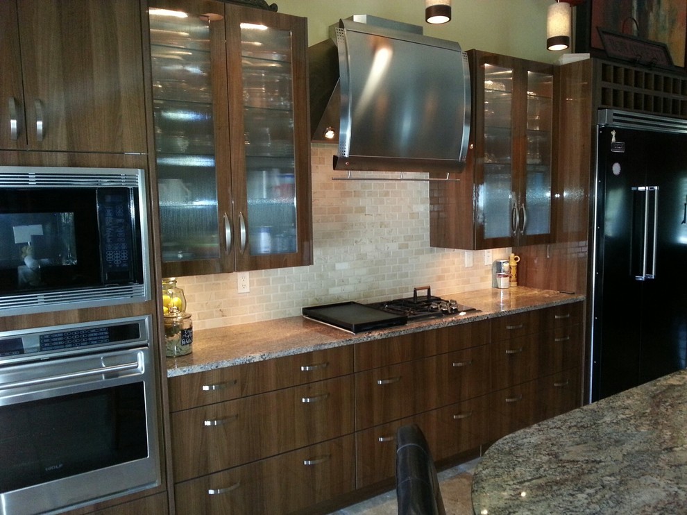Bild på ett funkis kök, med en undermonterad diskho, släta luckor, skåp i mörkt trä, bänkskiva i kalksten, svart stänkskydd, stänkskydd i stenkakel och färgglada vitvaror