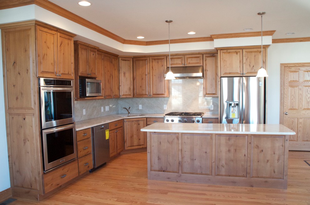 This is an example of a medium sized beach style l-shaped kitchen/diner in New York with beaded cabinets, medium wood cabinets, granite worktops, grey splashback, stainless steel appliances, medium hardwood flooring and an island.