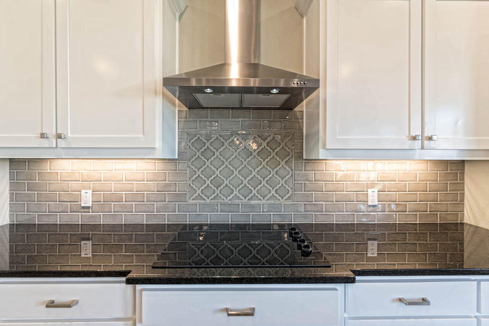 Mid-sized transitional l-shaped dark wood floor and beige floor enclosed kitchen photo in Austin with a double-bowl sink, shaker cabinets, white cabinets, granite countertops, gray backsplash, stainless steel appliances and an island