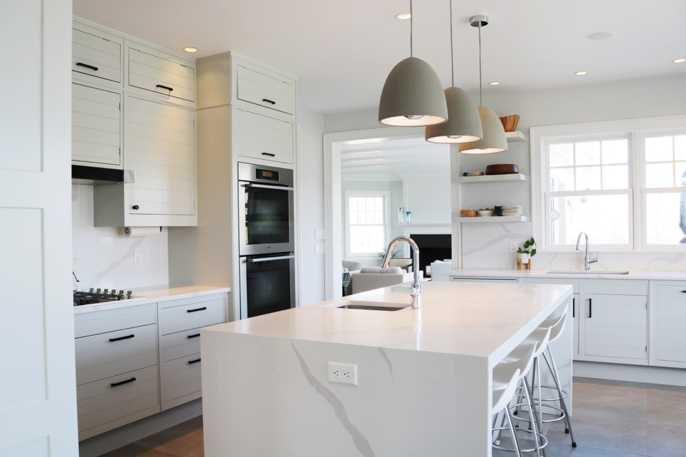 Exempel på ett stort klassiskt vit vitt l-kök, med en undermonterad diskho, vita skåp, vitt stänkskydd, rostfria vitvaror, en köksö, brunt golv och släta luckor