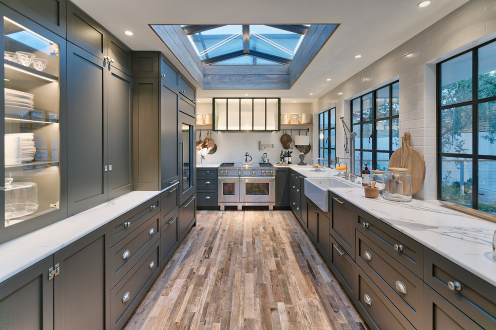 Example of a transitional u-shaped brown floor kitchen design in Orange County with shaker cabinets, gray cabinets, white backsplash, stainless steel appliances, no island and white countertops