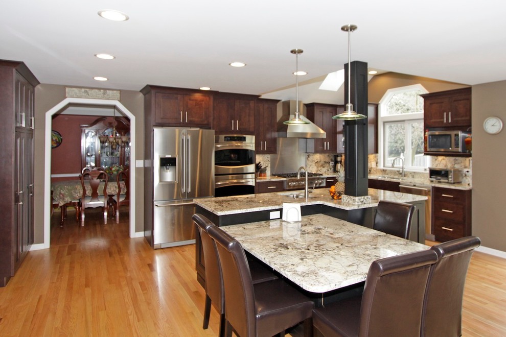 Example of a transitional l-shaped eat-in kitchen design in Chicago with an undermount sink, recessed-panel cabinets, distressed cabinets, granite countertops, multicolored backsplash, stone slab backsplash and stainless steel appliances