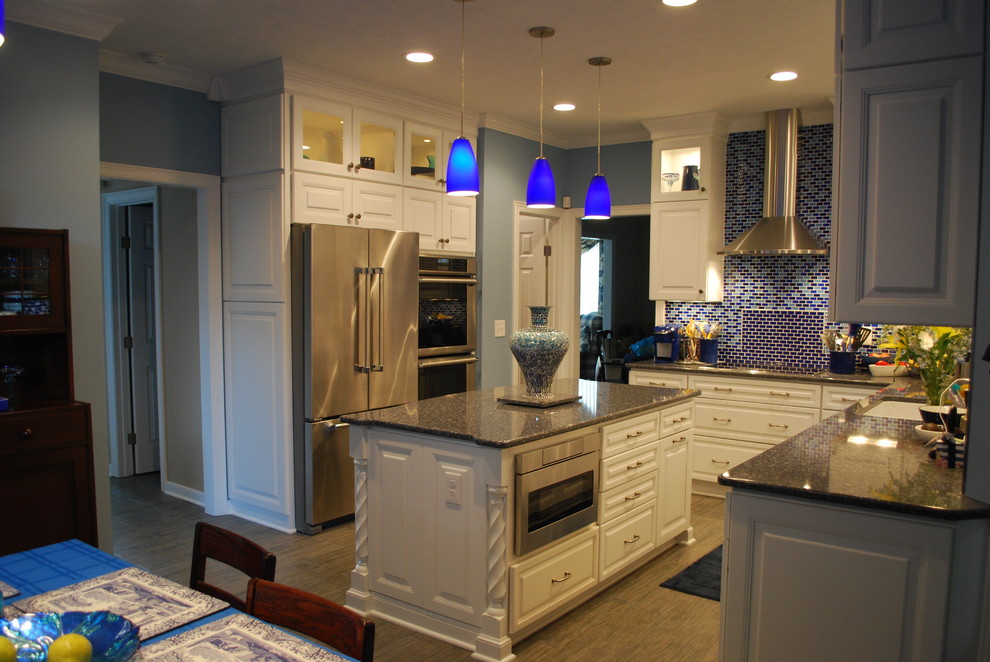 Exempel på ett stort klassiskt kök, med en undermonterad diskho, luckor med upphöjd panel, vita skåp, bänkskiva i kvarts, blått stänkskydd, stänkskydd i glaskakel, rostfria vitvaror, klinkergolv i porslin och en köksö