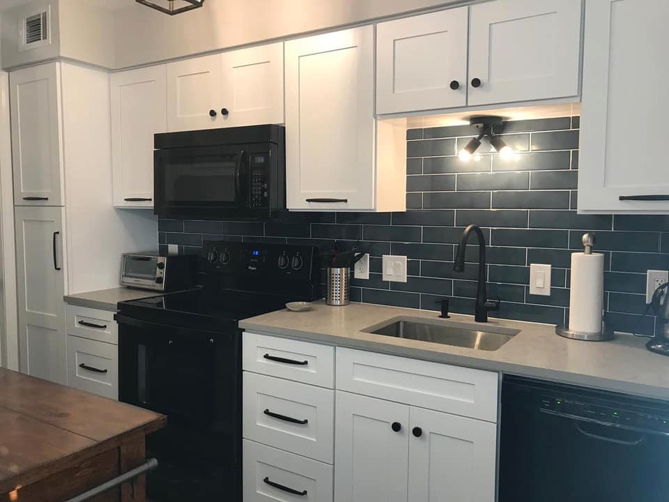 Idéer för att renovera ett litet industriellt grå linjärt grått kök och matrum, med en undermonterad diskho, luckor med infälld panel, vita skåp, bänkskiva i kvarts, blått stänkskydd, stänkskydd i keramik, svarta vitvaror och en köksö