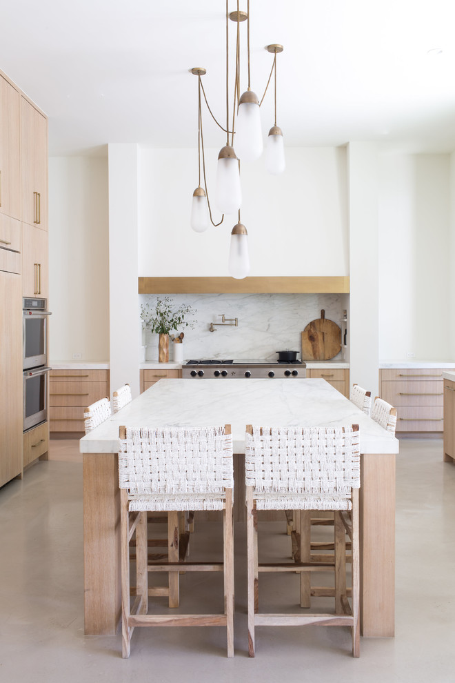 Modern inredning av ett stort vit vitt u-kök, med släta luckor, skåp i ljust trä, marmorbänkskiva, vitt stänkskydd, stänkskydd i sten, integrerade vitvaror, betonggolv, en köksö och grått golv