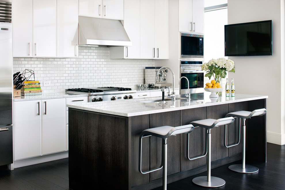 Moderne Küche mit Unterbauwaschbecken, weißen Schränken, Küchenrückwand in Weiß, Rückwand aus Metrofliesen, Küchengeräten aus Edelstahl, dunklem Holzboden und Kücheninsel in Austin