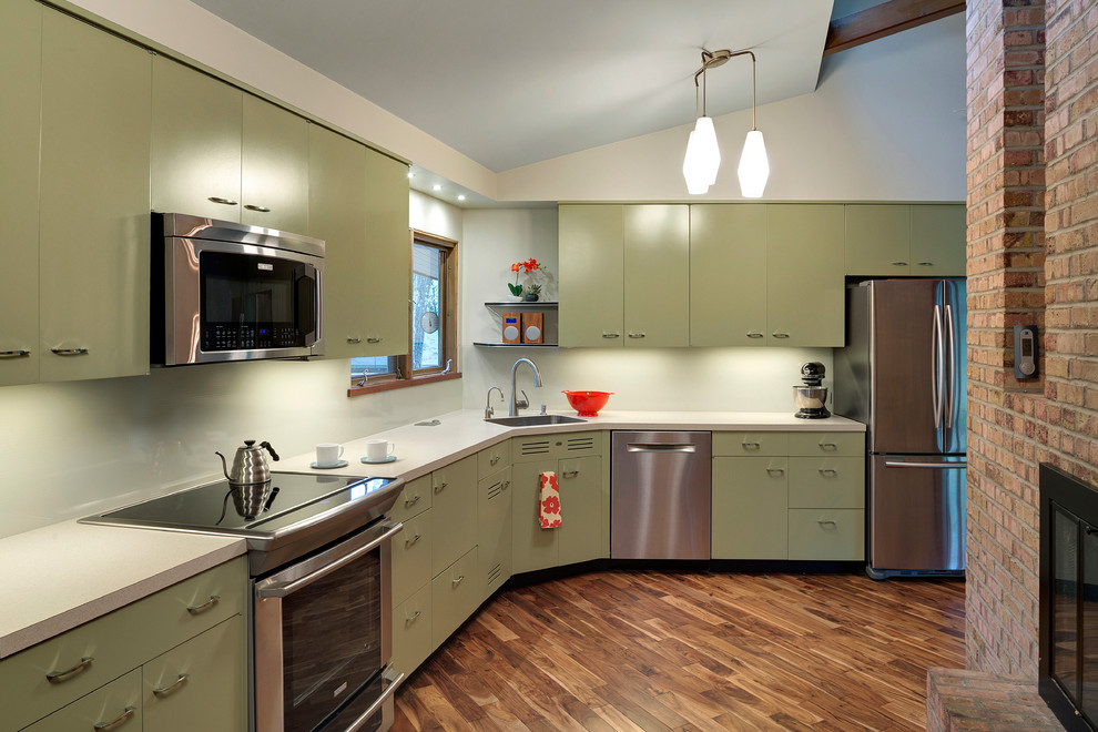 Inspiration for a mid-sized 1960s l-shaped medium tone wood floor kitchen remodel in Minneapolis with an integrated sink, green cabinets, laminate countertops, white backsplash, glass sheet backsplash, stainless steel appliances and no island