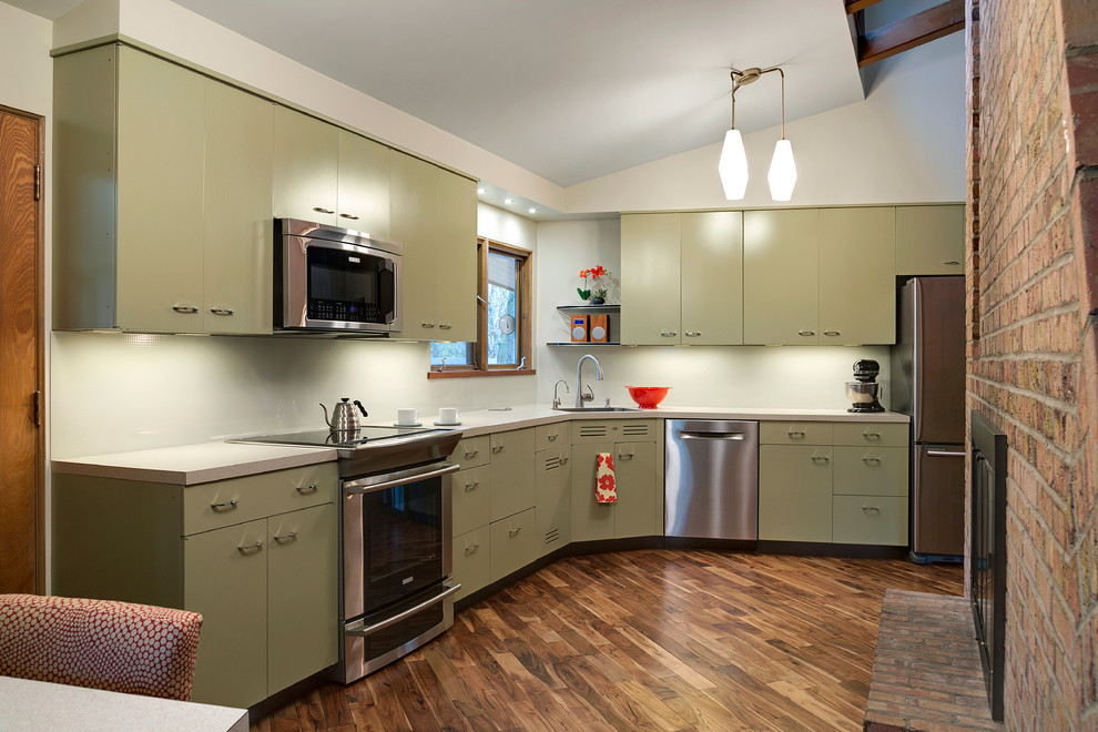 Mittelgroße Mid-Century Küche ohne Insel in L-Form mit integriertem Waschbecken, grünen Schränken, Laminat-Arbeitsplatte, Küchenrückwand in Weiß, Glasrückwand, Küchengeräten aus Edelstahl und braunem Holzboden in Minneapolis