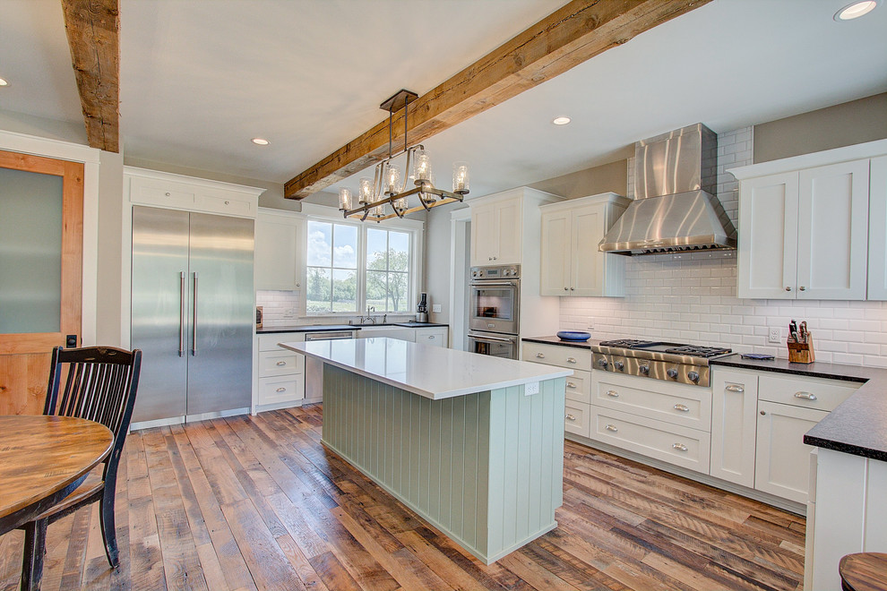 Inspiration for a farmhouse light wood floor, brown floor and wood ceiling enclosed kitchen remodel in Milwaukee with a farmhouse sink, flat-panel cabinets, green cabinets, granite countertops, white backsplash, subway tile backsplash, stainless steel appliances, an island and white countertops