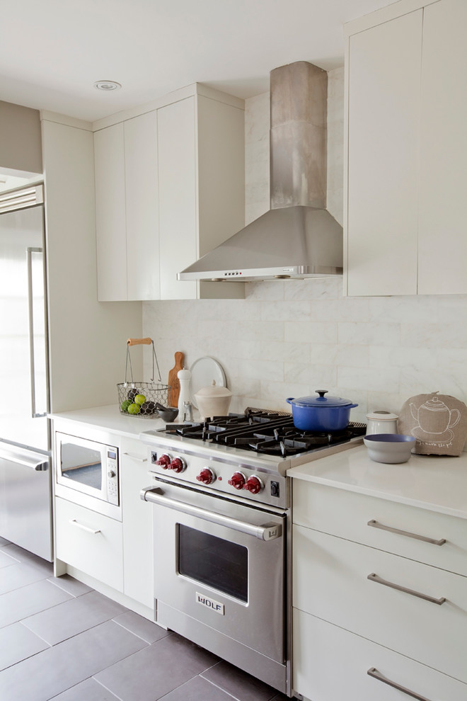 Ejemplo de cocina actual con salpicadero blanco, salpicadero de azulejos de piedra, electrodomésticos de acero inoxidable, armarios con paneles lisos y puertas de armario blancas