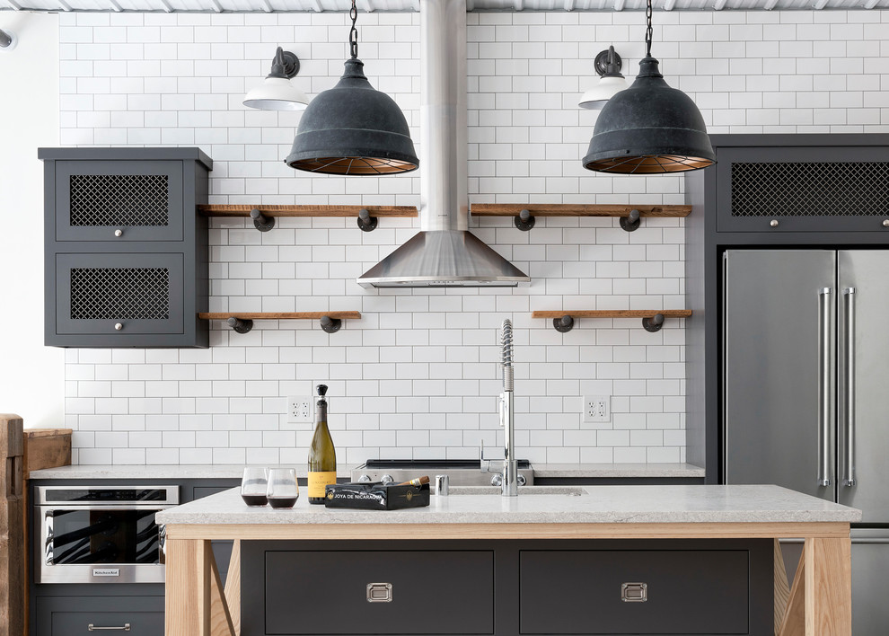 Industrial kitchen/diner in Minneapolis with open cabinets, medium wood cabinets, white splashback, stainless steel appliances, an island, brown floors and yellow worktops.