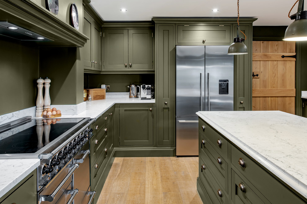 Große Klassische Küche in L-Form mit Schrankfronten im Shaker-Stil, Marmor-Arbeitsplatte, Küchengeräten aus Edelstahl, hellem Holzboden, Kücheninsel, weißer Arbeitsplatte, grünen Schränken, Küchenrückwand in Grün und beigem Boden in Sonstige