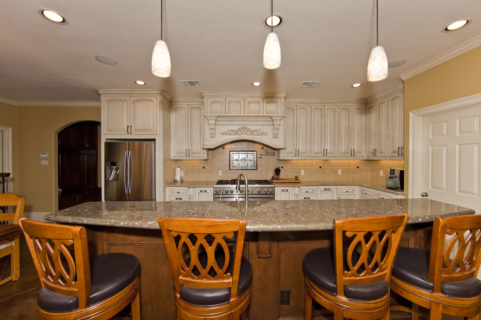 Elegant kitchen photo in Houston with an undermount sink, raised-panel cabinets, white cabinets, granite countertops, beige backsplash, ceramic backsplash and stainless steel appliances