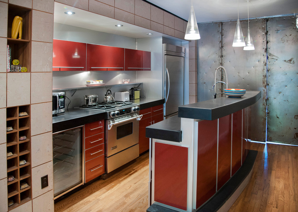 Diseño de cocina lineal urbana abierta con fregadero bajoencimera, armarios con paneles lisos, puertas de armario rojas, encimera de granito, salpicadero verde y electrodomésticos de acero inoxidable