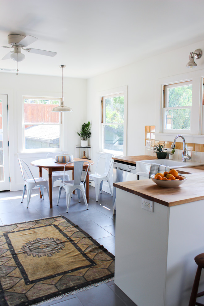 Foto på ett mellanstort retro kök, med skåp i shakerstil, vita skåp, träbänkskiva, orange stänkskydd, stänkskydd i keramik, rostfria vitvaror och en rustik diskho