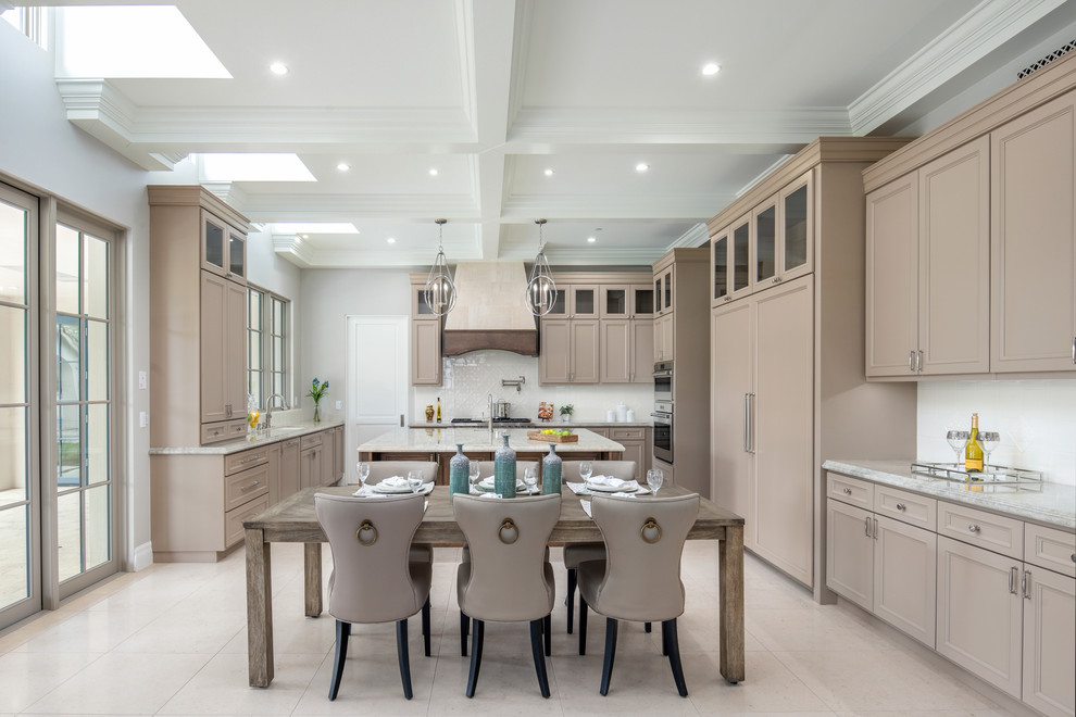 This is an example of a classic u-shaped kitchen/diner in Phoenix with a submerged sink, recessed-panel cabinets, beige cabinets, white splashback, integrated appliances, an island, beige floors and grey worktops.