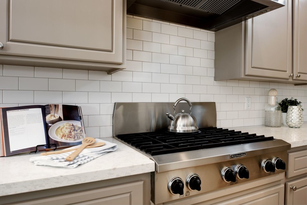 Foto på ett vintage kök, med en enkel diskho, grå skåp, bänkskiva i kvartsit, vitt stänkskydd, stänkskydd i keramik, rostfria vitvaror och en köksö
