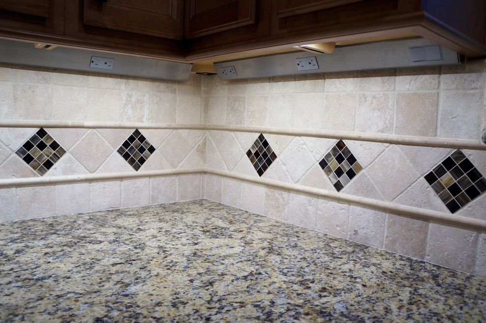 Klassisk inredning av ett kök och matrum, med en undermonterad diskho, luckor med infälld panel, skåp i mellenmörkt trä, granitbänkskiva, beige stänkskydd, stänkskydd i stenkakel, rostfria vitvaror och klinkergolv i keramik