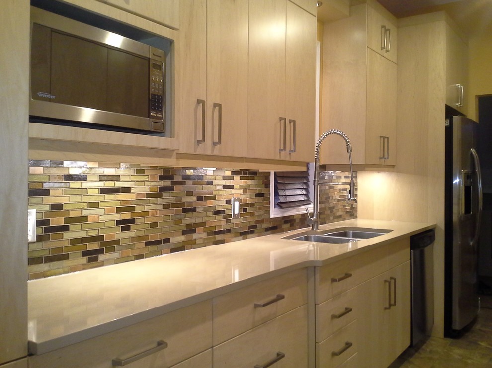 Example of a mid-sized transitional galley porcelain tile enclosed kitchen design in Ottawa with a double-bowl sink, flat-panel cabinets, light wood cabinets, multicolored backsplash, mosaic tile backsplash, stainless steel appliances, no island and solid surface countertops