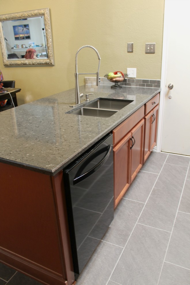 Idéer för att renovera ett litet industriellt kök, med en undermonterad diskho, luckor med infälld panel, skåp i mellenmörkt trä, bänkskiva i kvarts, stänkskydd med metallisk yta, stänkskydd i metallkakel, svarta vitvaror, klinkergolv i porslin, en halv köksö och grått golv