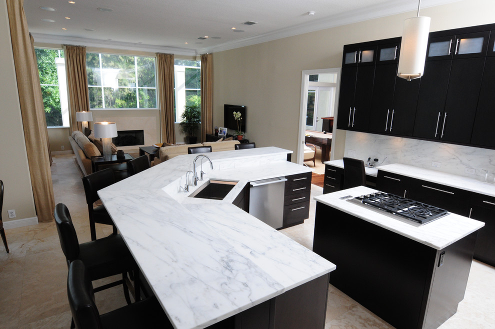 Example of a mid-sized transitional l-shaped porcelain tile and beige floor open concept kitchen design in Tampa with an undermount sink, flat-panel cabinets, black cabinets, marble countertops, white backsplash, stone slab backsplash, stainless steel appliances, two islands and gray countertops