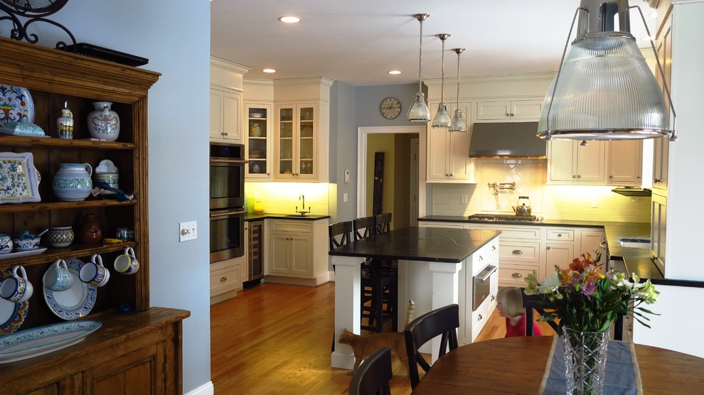 Inspiration for a large transitional l-shaped medium tone wood floor eat-in kitchen remodel in Bridgeport with a single-bowl sink, beaded inset cabinets, white cabinets, soapstone countertops, white backsplash, ceramic backsplash, stainless steel appliances, an island and black countertops