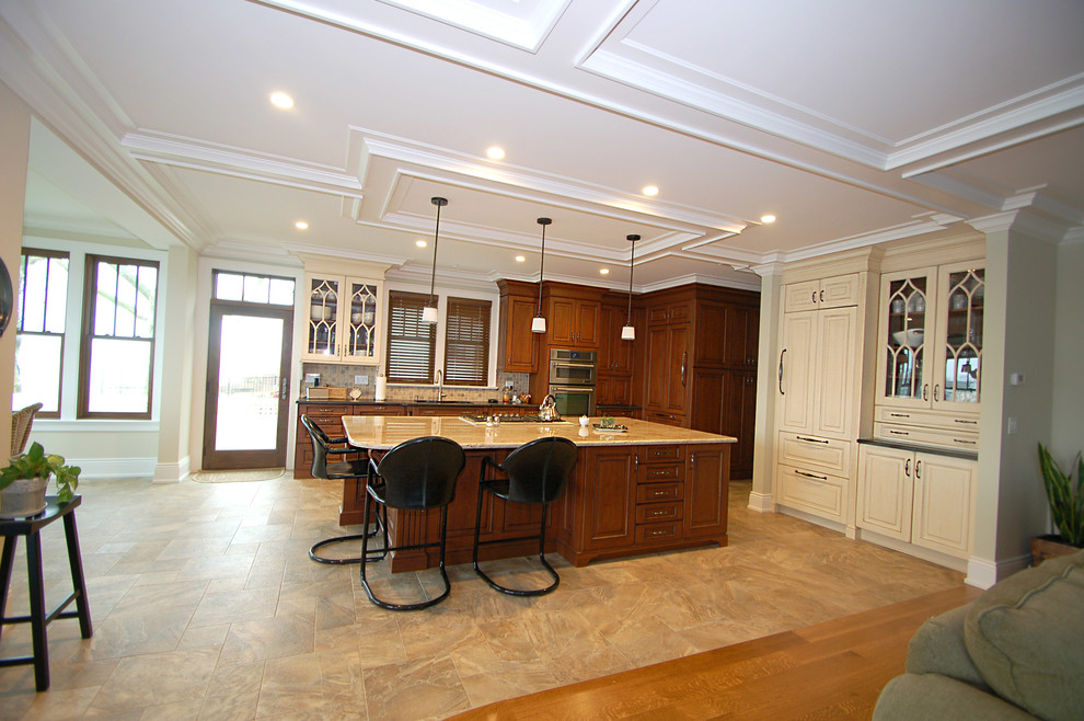 Exempel på ett stort klassiskt kök, med en undermonterad diskho, luckor med upphöjd panel, skåp i mellenmörkt trä, granitbänkskiva, beige stänkskydd, stänkskydd i mosaik, integrerade vitvaror, klinkergolv i porslin och en köksö