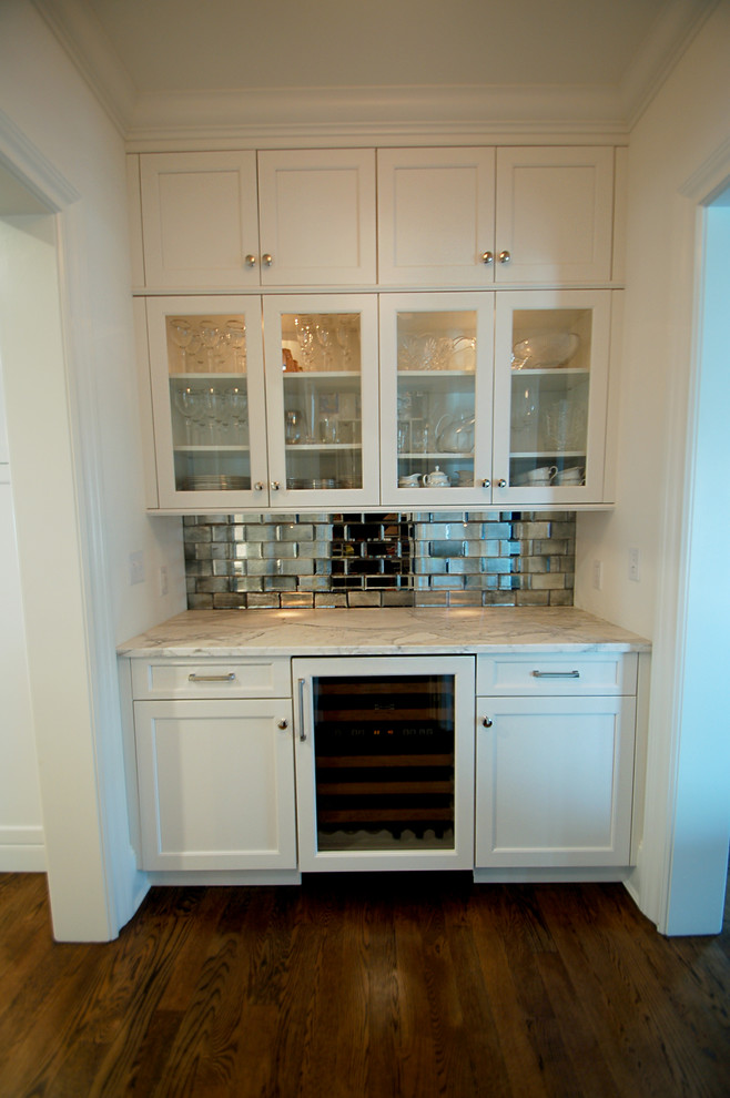 This is an example of a large traditional l-shaped home bar in New York with a submerged sink, recessed-panel cabinets, white cabinets, marble worktops, white splashback, metro tiled splashback and medium hardwood flooring.
