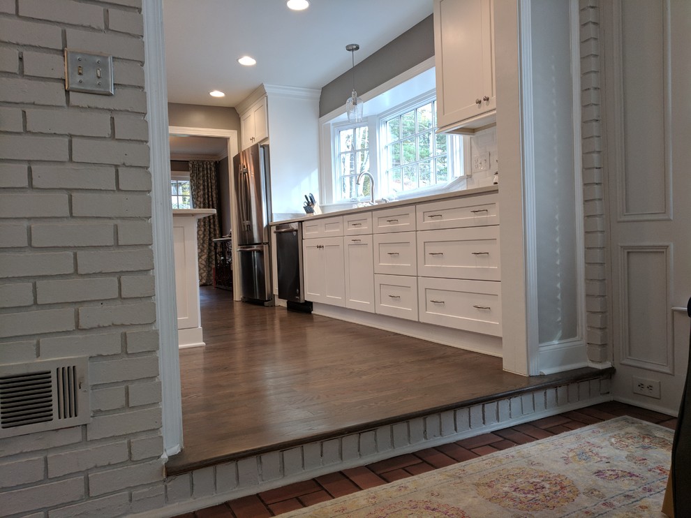 Eat-in kitchen - mid-sized transitional u-shaped dark wood floor and brown floor eat-in kitchen idea in Atlanta with an undermount sink, shaker cabinets, white cabinets, solid surface countertops, white backsplash, subway tile backsplash, stainless steel appliances and a peninsula