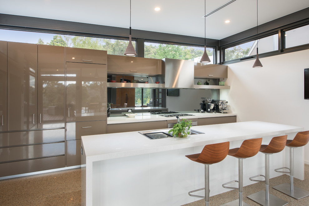 Bild på ett mycket stort funkis kök, med en integrerad diskho, släta luckor, bruna skåp, granitbänkskiva, spegel som stänkskydd, rostfria vitvaror, betonggolv och en köksö